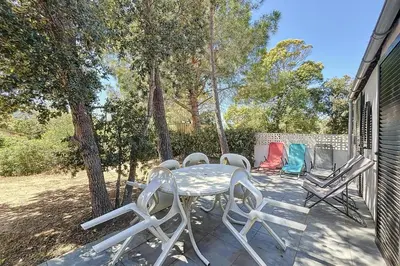 a table and chairs on a patio with trees at Mini Villa At 150m From The Beach Of Santa Giulia in Porto-Vecchio