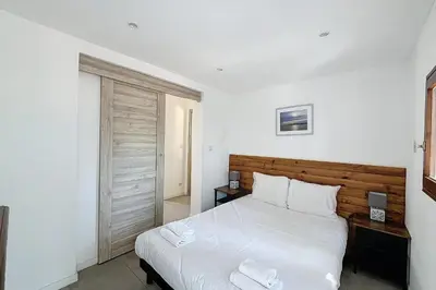 a bedroom with a large white bed with a wooden headboard at Mini Villa At 150m From The Beach Of Santa Giulia in Porto-Vecchio