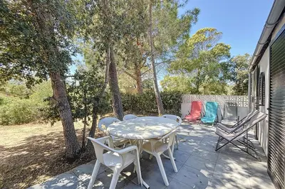 a patio with a table and chairs and trees at Mini Villa At 150m From The Beach Of Santa Giulia in Porto-Vecchio