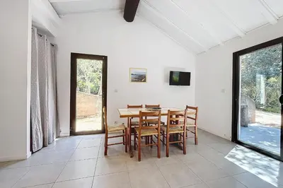 a dining room with a wooden table and chairs at Mini Villa At 150m From The Beach Of Santa Giulia in Porto-Vecchio