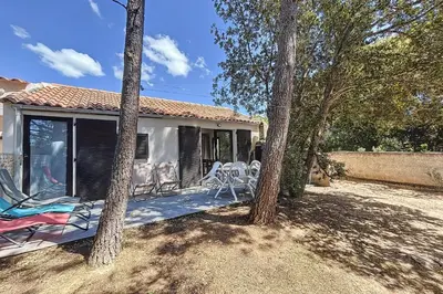 a house with a porch with chairs and trees at Mini Villa At 150m From The Beach Of Santa Giulia in Porto-Vecchio