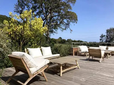 a deck with several chairs and a table and a table and chairs at Les Lofts de Sainte-Lucie-de-Porto-Vecchio in Sainte-Lucie de Porto-Vecchio