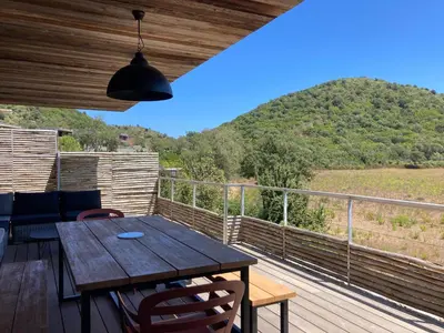 a wooden table on a deck with a view of a mountain at Les Lofts de Sainte-Lucie-de-Porto-Vecchio in Sainte-Lucie de Porto-Vecchio
