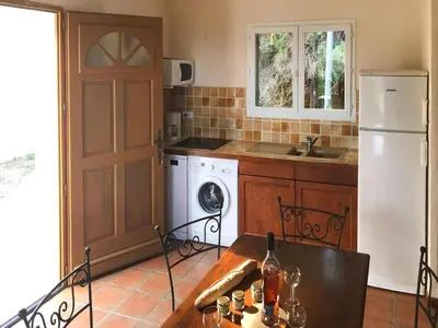 a kitchen with a refrigerator and a table with wine glasses at Apartment in Corsica near Sandy Beach in Favone