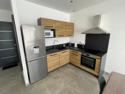 a kitchen with a stainless steel refrigerator and wooden cabinets at CLOS ARIA NOVA in Lucciana