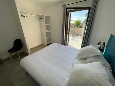 a bedroom with a large white bed and a balcony at CLOS ARIA NOVA in Lucciana