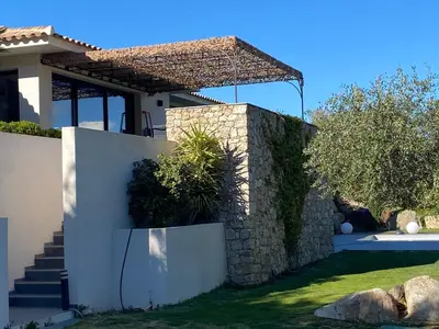a house with a stone wall and a fence at Villa Récente avec Piscine proche L'ILE ROUSSE in Ville-di-Paraso