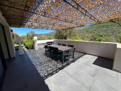 a patio with a table and chairs under a roof at Villa Récente avec Piscine proche L'ILE ROUSSE in Ville-di-Paraso