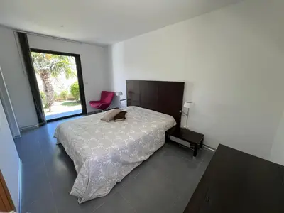 a bedroom with a bed and a pink chair at Villa Récente avec Piscine proche L'ILE ROUSSE in Ville-di-Paraso