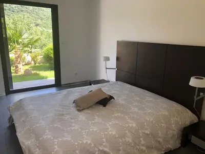 a bedroom with a large bed with a large window at Villa Récente avec Piscine proche L'ILE ROUSSE in Ville-di-Paraso