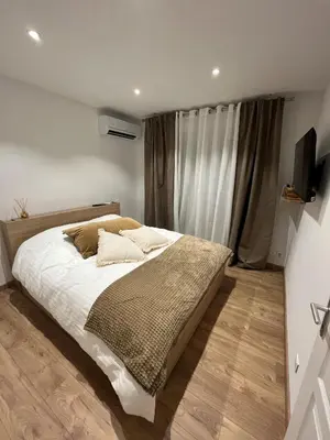 a bedroom with a bed with white sheets and a television at Charmant T2 refait à neuf in Ajaccio