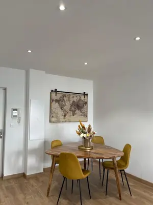 a dining room with a wooden table and yellow chairs at Charmant T2 refait à neuf in Ajaccio