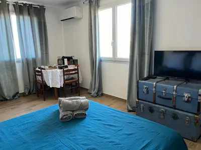 a bedroom with a bed with a blue blanket and a table at Casa Rosalinda in Figari