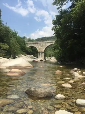 a bridge over a river with rocks in the water at Strada di a cuma in Vico