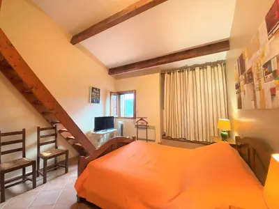 a bedroom with an orange bed and a staircase at Duplex Belvédère-Campomoro, vue mer in Belvédère