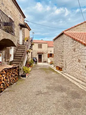 an alleyway between two stone buildings with a car parked at Duplex Belvédère-Campomoro, vue mer in Belvédère