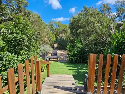 a wooden walkway leading to a garden with a bench at Ma cabane au fond du jardin in Porto-Vecchio