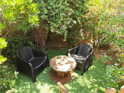 three black chairs and a table in the grass at Ma cabane au fond du jardin in Porto-Vecchio