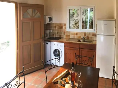 a kitchen with a refrigerator and a table with wine glasses at Res Mare e Monte, Solenzara, Bungalow with terrace in Favone