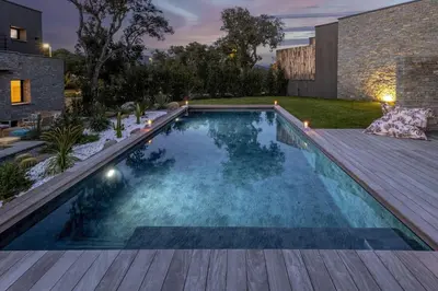 a swimming pool in a backyard with a wooden deck at Villa Renajolo 10 pers piscine chauffée 2 min plage en voiture in Sainte-Lucie de Porto-Vecchio
