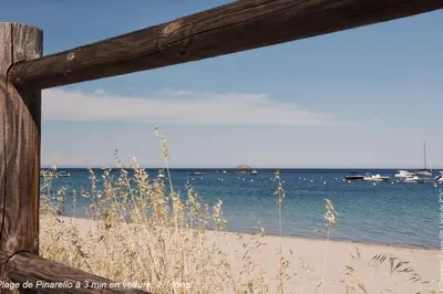 a view of the beach through a wooden window at Villa Renajolo 10 pers piscine chauffée 2 min plage en voiture in Sainte-Lucie de Porto-Vecchio