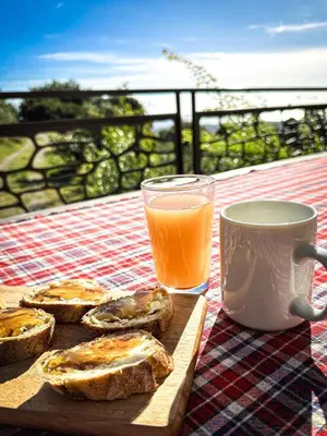 a table with a plate of bread and a glass of orange juice at Eco Gîte avec vue sur mer in Chiatra