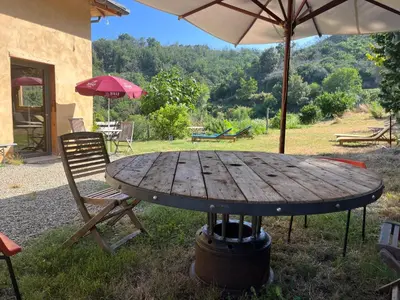 a wooden table with a chair and an umbrella at Eco Gîte avec vue sur mer in Chiatra