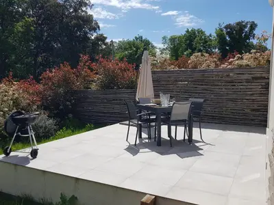a patio with a table and chairs and an umbrella at Maisons T2 avec jardins privatifs - 10mn de la plage et 5mn du village - Casa di i trinelli in Vescovato