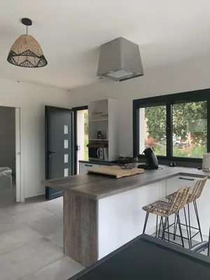 a kitchen with a counter and two stools at Maisons T2 avec jardins privatifs - 10mn de la plage et 5mn du village - Casa di i trinelli in Vescovato
