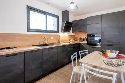 a kitchen with black cabinets and a wooden table at Villa Renajolo 6 pers 3 min plage en voiture in Sainte-Lucie de Porto-Vecchio