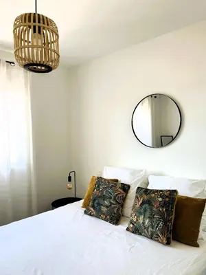 a bedroom with a white bed with a mirror on the wall at Sognu di Serena - Superbe appartement avec parking gratuit sur place in Porto-Vecchio