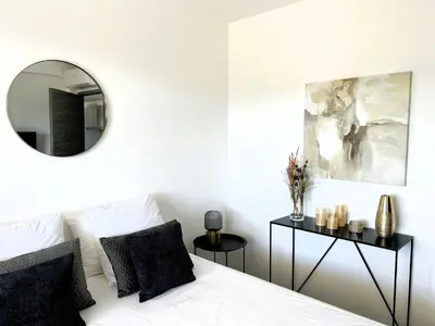a bedroom with a white bed and a mirror at Sognu di Serena - Superbe appartement avec parking gratuit sur place in Porto-Vecchio