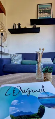 a living room with a blue couch and a table at L'Original, Superbe appartement à 5min de la plage in Zonza