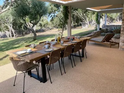 a long wooden table with chairs on a patio at Villa Arbevhio in Bonifacio