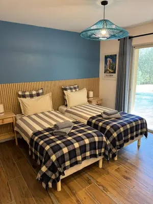 a bedroom with two beds and a blue wall at Villa Arbevhio in Bonifacio
