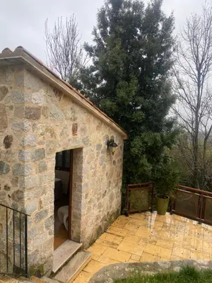 a stone building with an open door on a patio at CHAMBRES D'HOTES CENTRE CORSE in Venaco