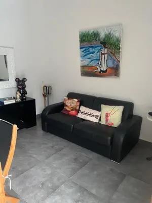 a black couch in a living room with a painting at CHAMBRES D'HOTES CENTRE CORSE in Venaco