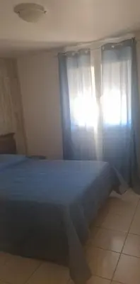 a bedroom with a bed with blue sheets and a window at corse in Appietto