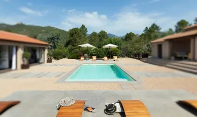 a swimming pool with benches and umbrellas in a backyard at **** VILLA CASA DI FIUMU **** in Porto-Vecchio