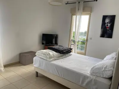a bedroom with a bed with a television and a window at Superbe appartement avec parking privé, proche commerces et mer in Lucciana