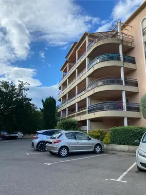 two cars parked in a parking lot in front of a building at Superbe appartement avec parking privé, proche commerces et mer in Lucciana