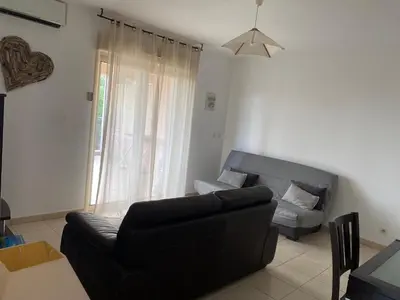 a living room with a black couch and a window at Superbe appartement avec parking privé, proche commerces et mer in Lucciana