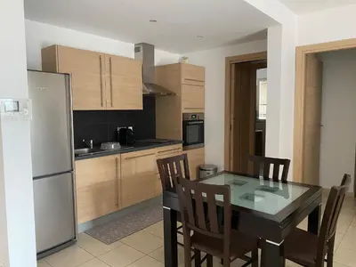 a kitchen with a table and chairs and a refrigerator at Superbe appartement avec parking privé, proche commerces et mer in Lucciana