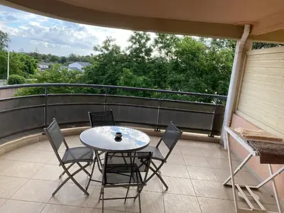 a patio with a table and chairs on a balcony at Superbe appartement avec parking privé, proche commerces et mer in Lucciana