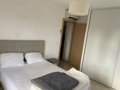 a bedroom with a white bed with a gray blanket at Superbe appartement avec parking privé, proche commerces et mer in Lucciana