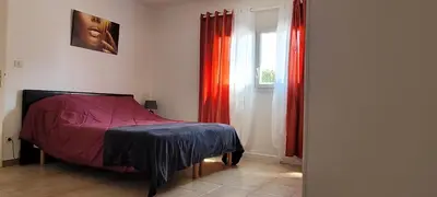 a bedroom with a bed with red curtains and a window at 