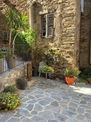 a stone building with a table and plants in front of it at Levé du soleil sur la mer in Taglio-Isolaccio