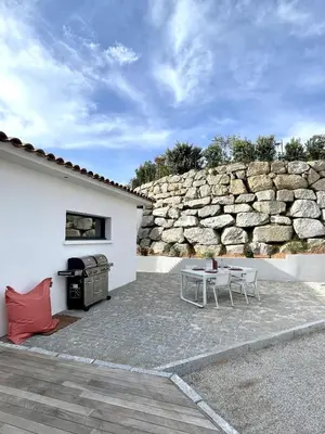 a patio with a table and a stone wall at Villa U Pastore in Porticcio
