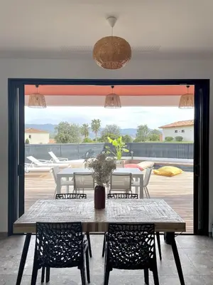 a dining room with a table and chairs and a large window at Villa U Pastore in Porticcio