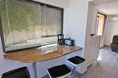a kitchen with a counter with stools and a window at Douceur du soir - Duplex 45m2 - Terrasse - Jardinet - Wifi fibre - Plage à pied in Porticcio